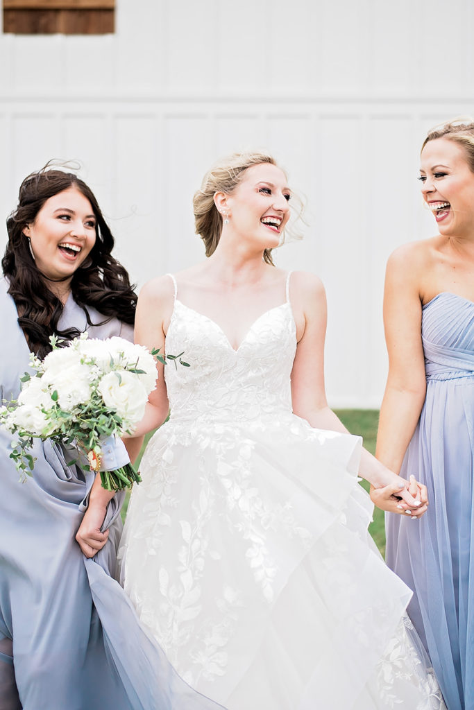 Candid photo bride with bridesmaid with periwinkle dresses hand in hand