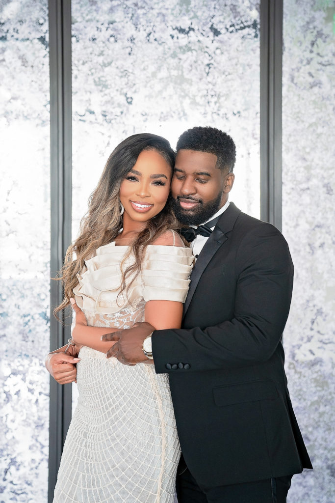 Retro Hollywood Glamor Engagement Session at The Revarie Houston with Black Couple hugging in high end cream gown and classic black tux