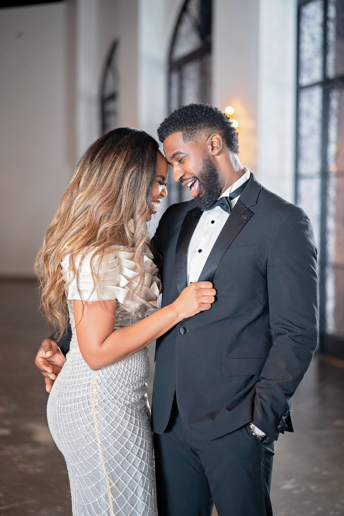 Retro Hollywood Glamor Engagement Session at The Revarie Houston with Black Couple laughing in high end cream gown and classic black tux