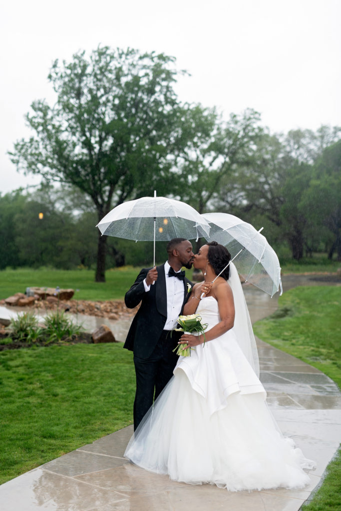 Bride and groom kissing in rain with umbrellas Highpointe Estates wedding Georgetown Texas Kate Rose Creative Group/Katelyn Lakey