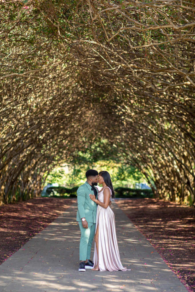 standing canopy photo with engaged couple kissing under a tree arch