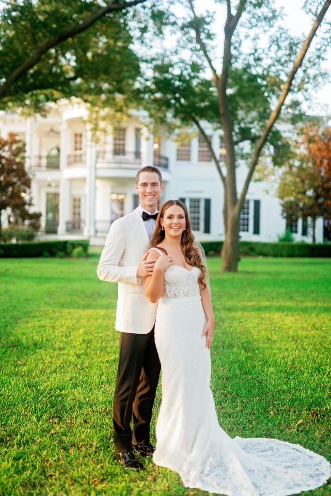 bride and groom pose in front of their venue at the Sandlewood Manor