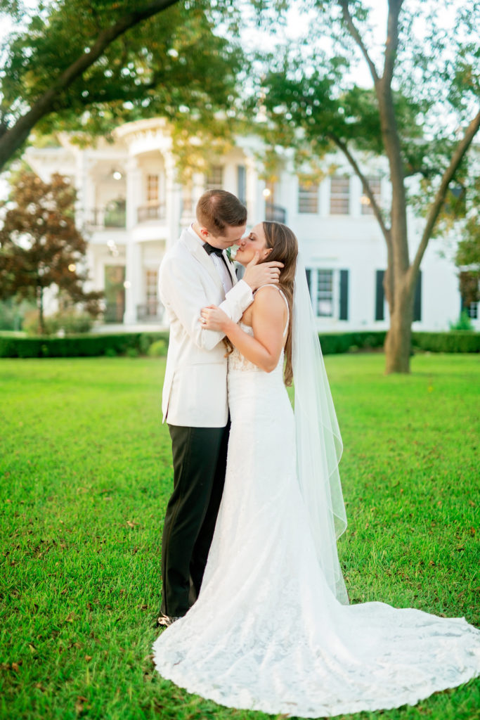 timeless wedding newlywed couple kiss in front of their venue at the Sandlewood Manor