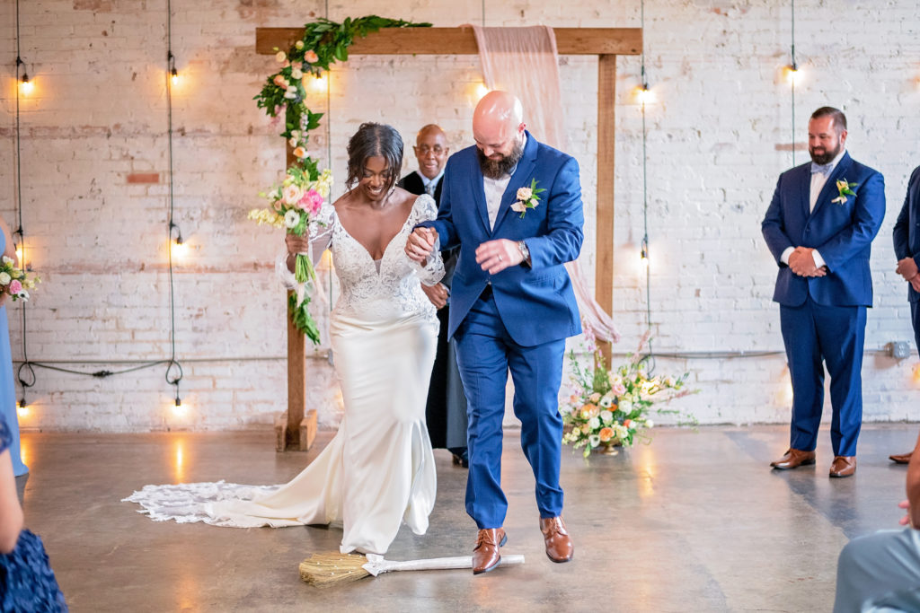 bride and groom jumping over the broom at Brake and Clutch Warehouse Wedding