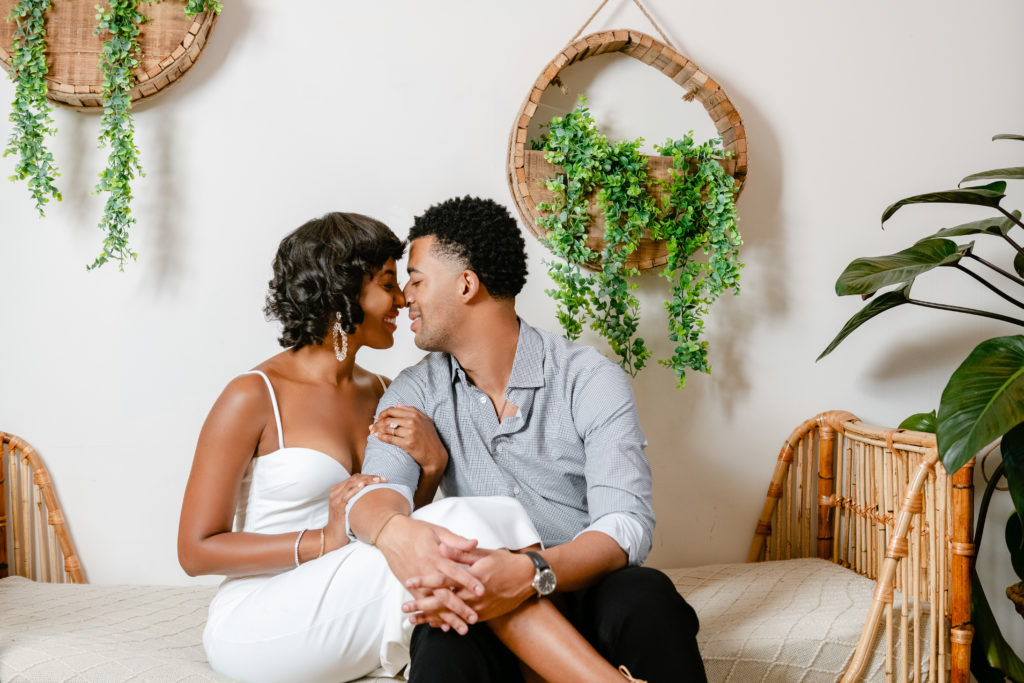 engagement photo session, sitting down poses, neutral background, indoor photoshoot, greenery, white dress, men engagement outfit
