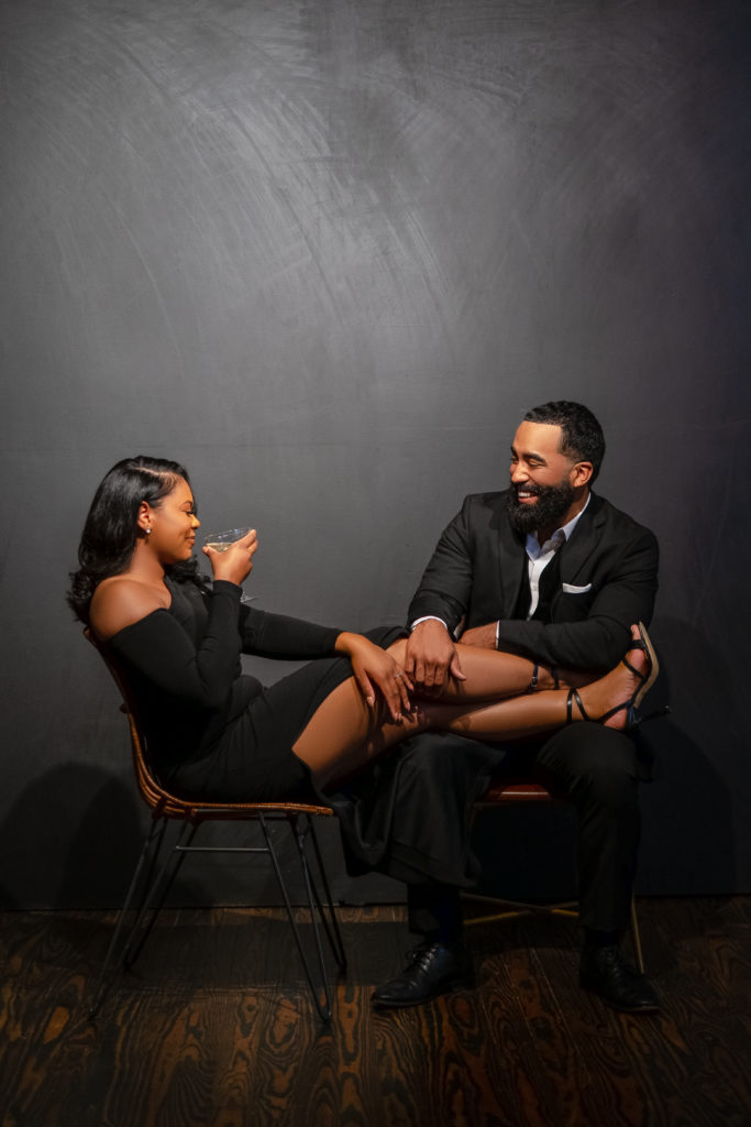Engagement session, couple poses, loft location, houston photoshoot, black couple, all black attire , glamour engagement outfit, sitting down poses, champagne